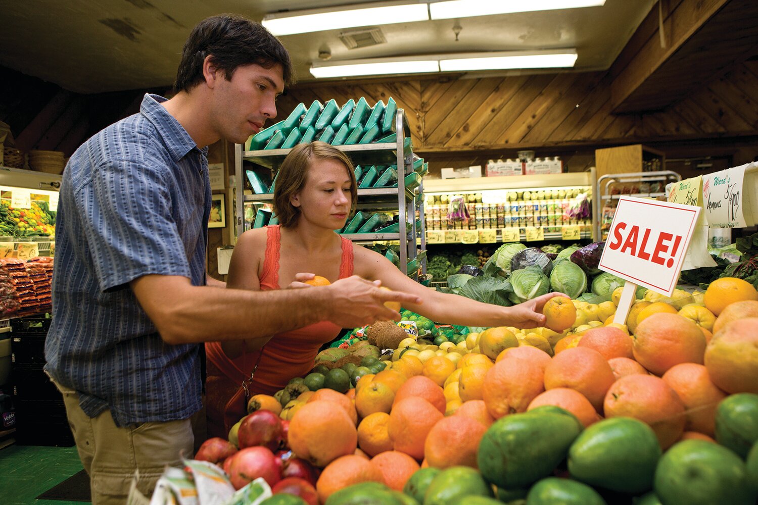 Two customers checking produce in a grocery store.